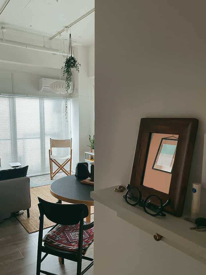 白とナチュラルカラーの小さなリビング兼ダイニングスペース、シンプルな家具と植物が配置された落ち着いた雰囲気のあるインテリア