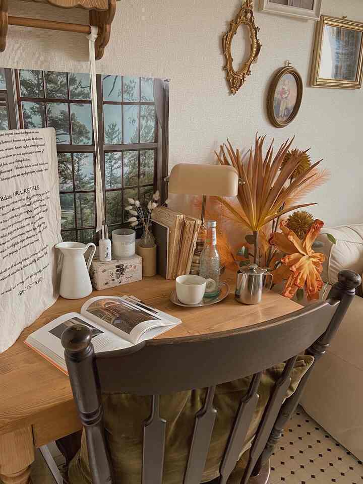 ベージュの壁と天然木のテーブル、アンティークのテーブルランプが配置されたカフェ風のナチュラルなワークスペース