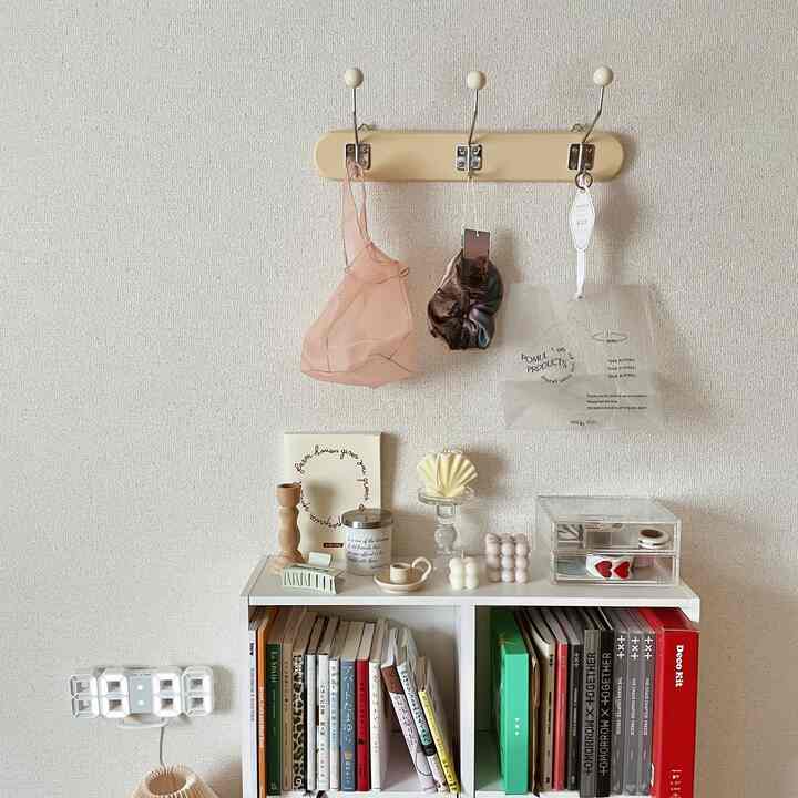 Minimal living space in white and wood tones featuring a wood wall hanger with candles creating a cozy atmosphere