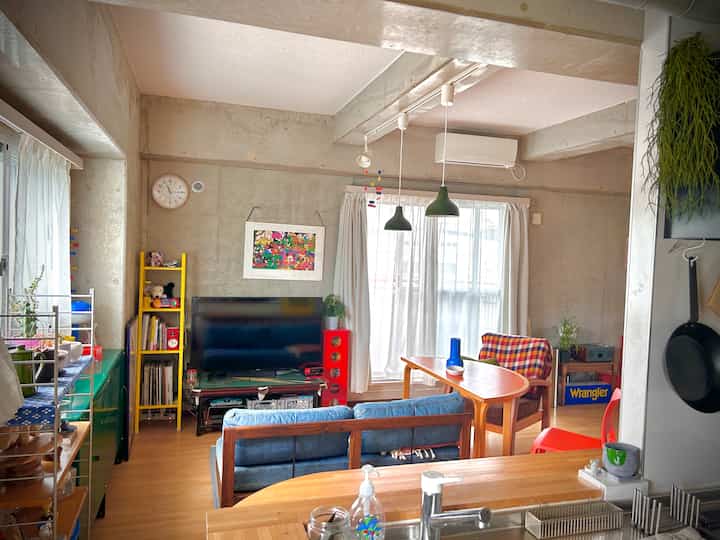 Natural-toned living room featuring concrete walls, wooden furniture, and green plants with a modern cozy atmosphere
