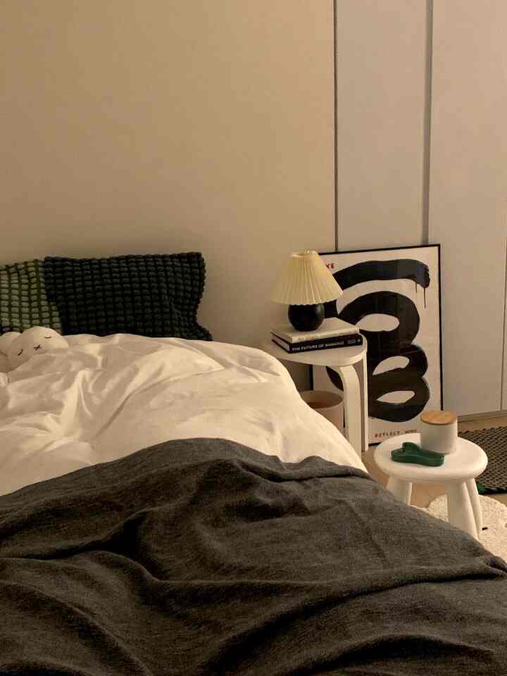 Natural tone bedroom featuring white bedding, stools, and black pillows creating a cozy atmosphere