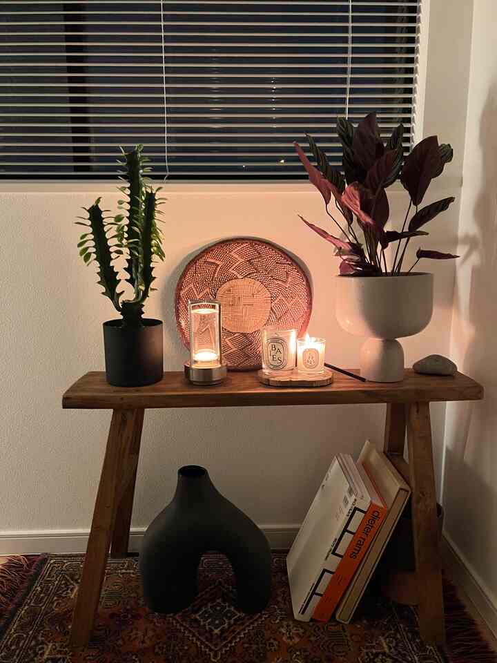 ナチュラルカラーの空間、木製ベンチの上にキャンドル2つと植物が配置され、温かみのある雰囲気のあるインテリア