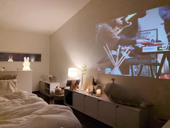 温かい照明と白い家具が配置されたシンプルで居心地の良い一人暮らしの寝室空間