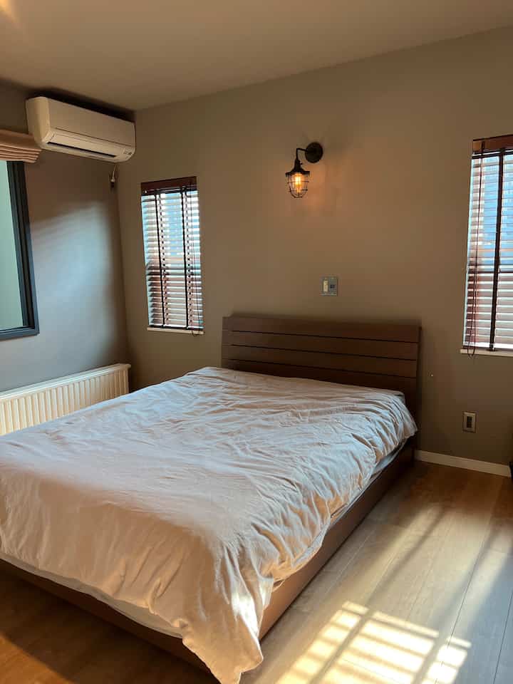 A natural wood tone and white bedroom featuring a bed centered with wall sconce lighting, creating a cozy atmosphere