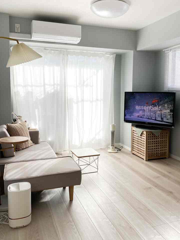 明るいホワイトカーテンのあるモダンでナチュラルな色調のリビング、ライトブラウンの木目床とソファが配置された雰囲気のあるインテリア