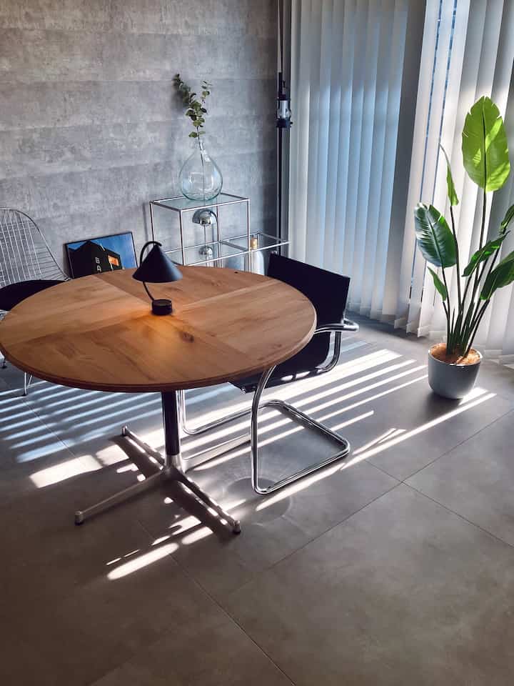 Natural tone dining room featuring a round table and table lamp centrally placed with a modern atmosphere