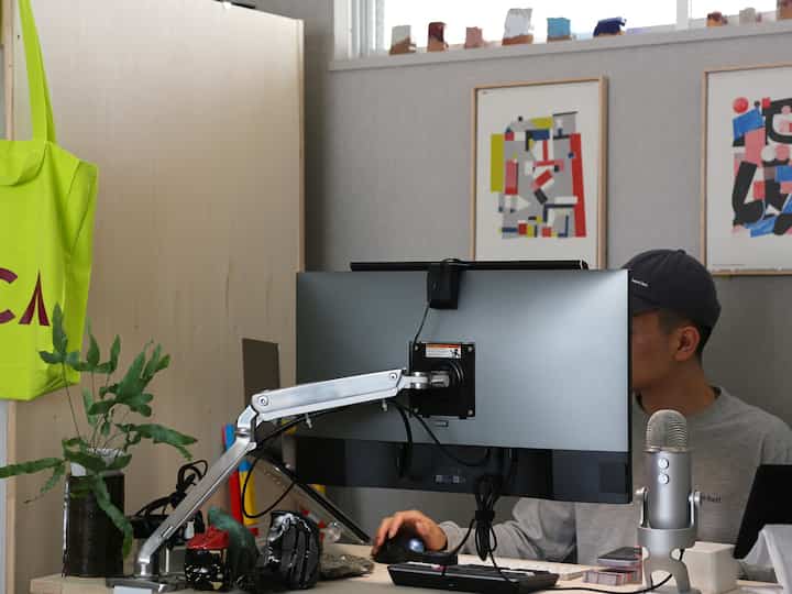 Gray-toned compact home office workspace featuring desk, monitor with arm mount, and USB microphone