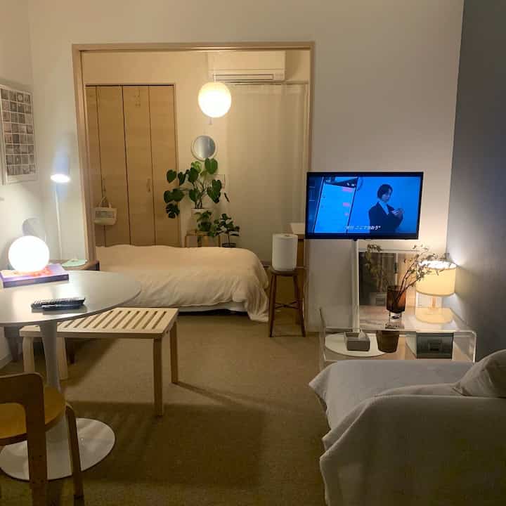 ベージュ色調のコンパクトなワンルーム、ナチュラルな家具とカーペットが配置された雰囲気のあるインテリア