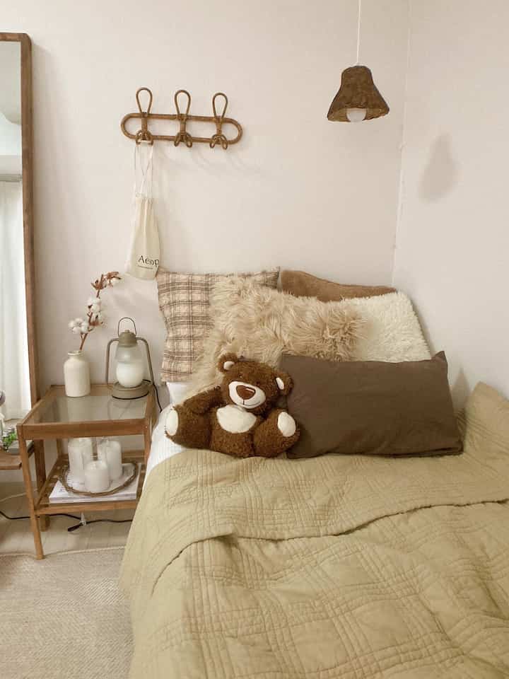 Beige and brown toned bedroom featuring a cozy bed with plush cushions and a teddy bear