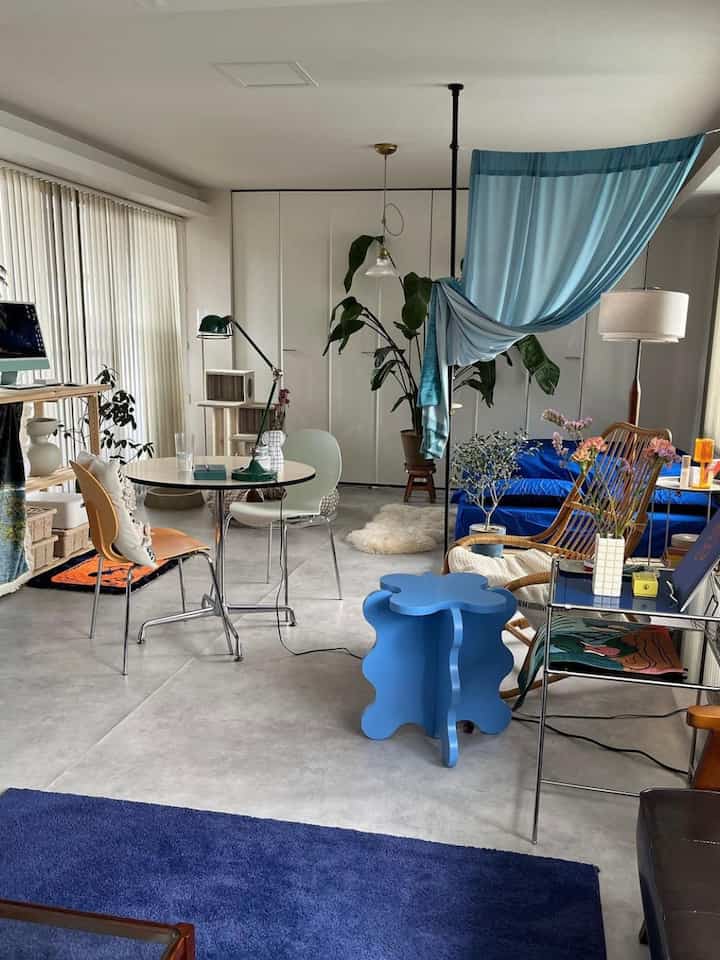 ブルーとグリーンのトーンが調和するダイニング兼リビングルーム、ミッドセンチュリーモダン家具と自然素材が配された雰囲気のある空間