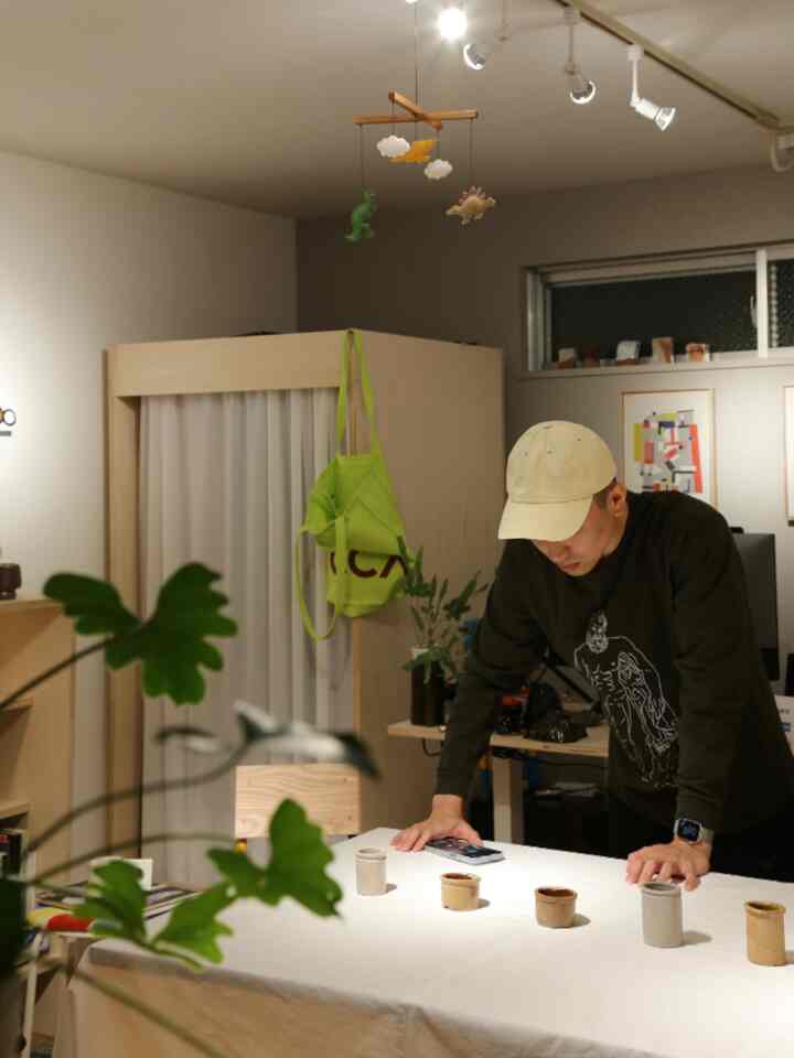 白いテーブルクロスが敷かれたワンルームのダイニングテーブルとキャップをかぶった男性がいる、自然でモダンな雰囲気のインテリア