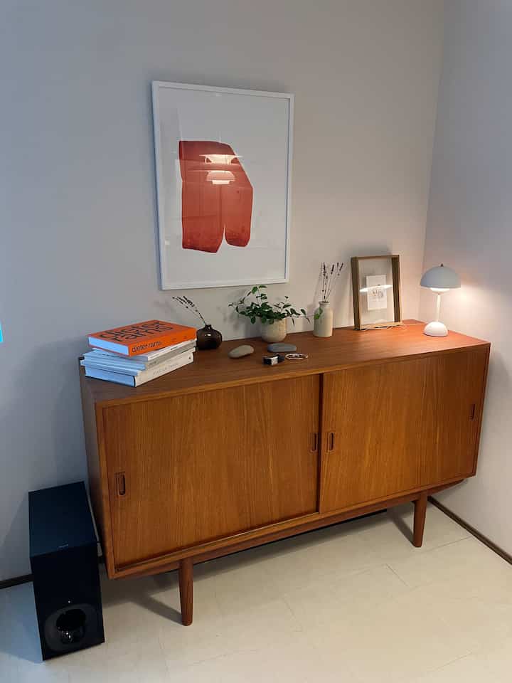 A brown wood-toned living room featuring a sideboard with an abstract poster on the wall, presenting a cozy atmosphere