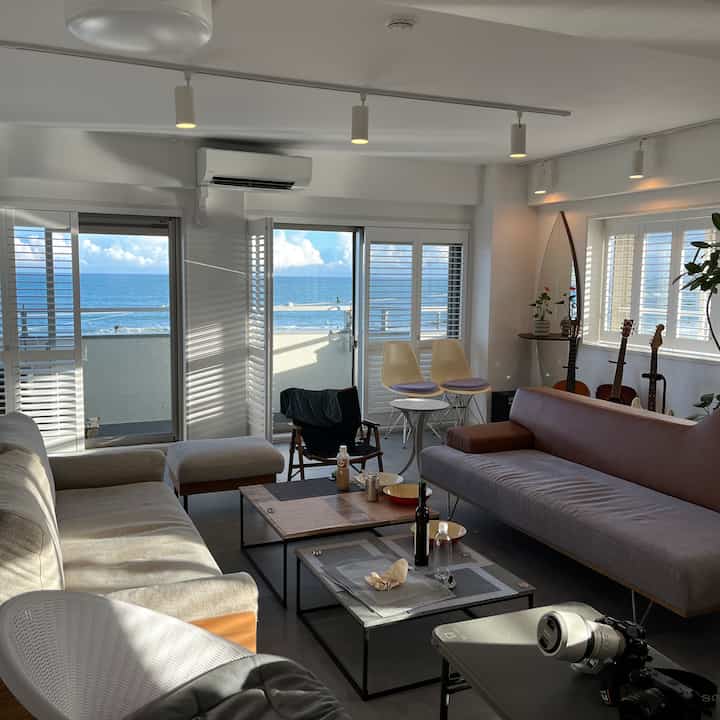 Brown and white toned living room featuring two sofas and a surfboard-shaped mirror with a natural ambiance