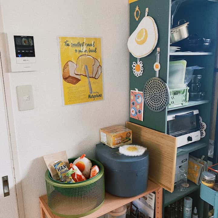 ナチュラルカラーと木目調のキッチンの一角に、ヴィンテージ風の食パンポスターや整理された調理道具が配置された印象的な空間