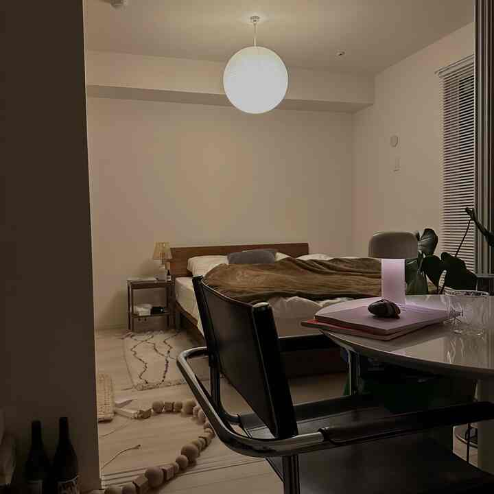 柔らかな照明の小さな寝室、木目調のベッドとペンダントライトが配置されたモダンな空間