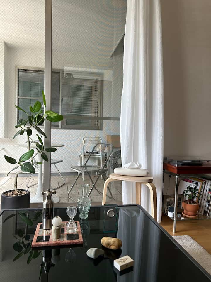 白とナチュラルカラーのリビング、ガラス製品と植物が配置された落ち着いた雰囲気のインテリア