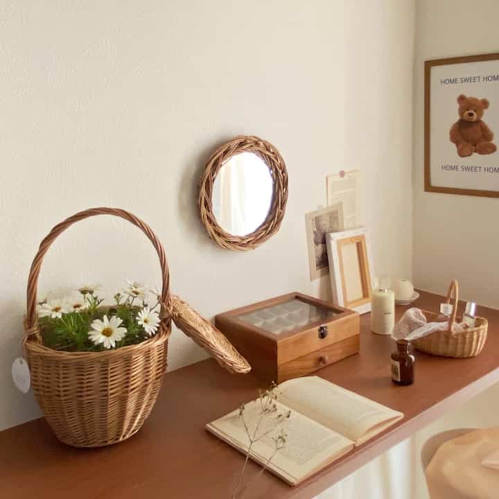 A wood tone natural walk-in closet dressing space featuring wicker baskets, a round wicker-framed mirror, wooden accessories creating a warm and cozy atmosphere