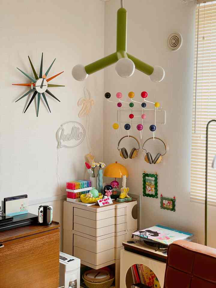 白い壁と黄色のアクセントが映える、小さなレトロ風コーナースペース。ミッドセンチュリーモダンの雰囲気あるインテリア。