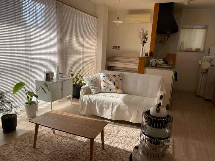 明るいホワイトと木目調が調和したリビング、ソファとテーブル、ヒーターが配置された暖かな雰囲気のインテリア