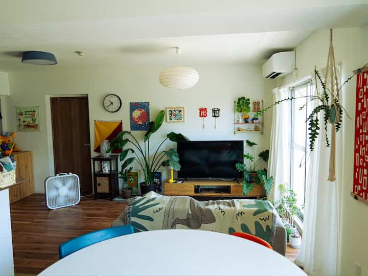 Natural wood tone and white-walled living room featuring green plants and a round dining table with cozy atmosphere