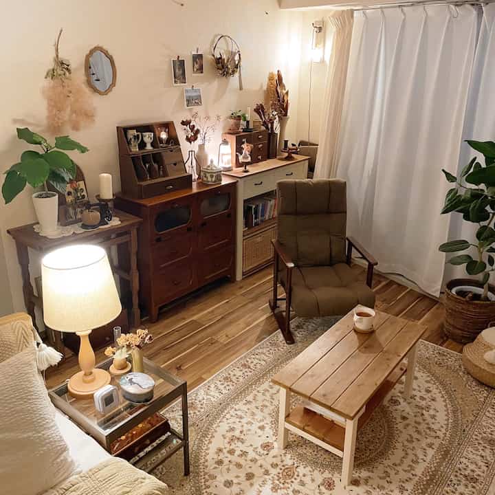 ナチュラルなブラウン調のリビング、木製のナイトテーブルとラグ、アームチェアとテーブルランプが配置された雰囲気のあるインテリア