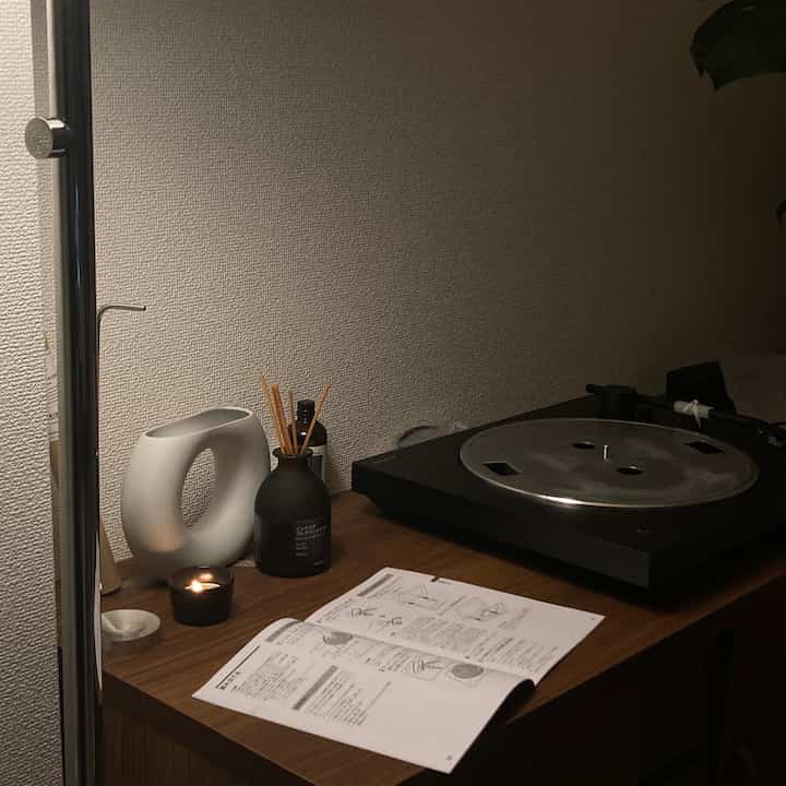 温かみのある木目調のデスクに配置されたソニーのレコードプレーヤーとキャンドル、ディフューザーが印象的なシンプルで自然な雰囲気のインテリア