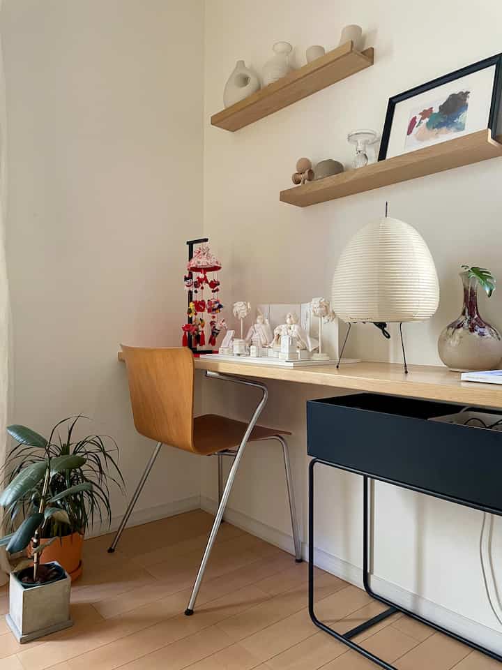 白と木目調が調和したミニマルなワークスペース、机の上にやわらかな照明と飾りが配置された雰囲気のあるインテリア