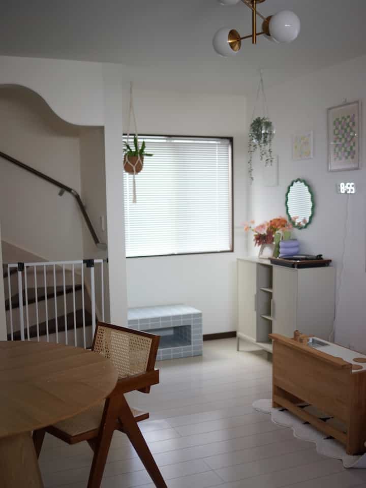 White and wood tone dining room featuring rattan chairs and round dining table in a baby-friendly, clean space