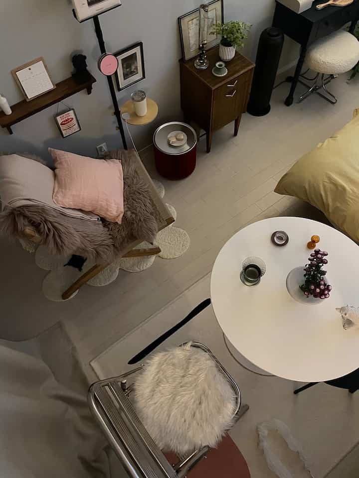 White and brown toned living room featuring a round table, cushioned chair with fur, and simple cozy decor