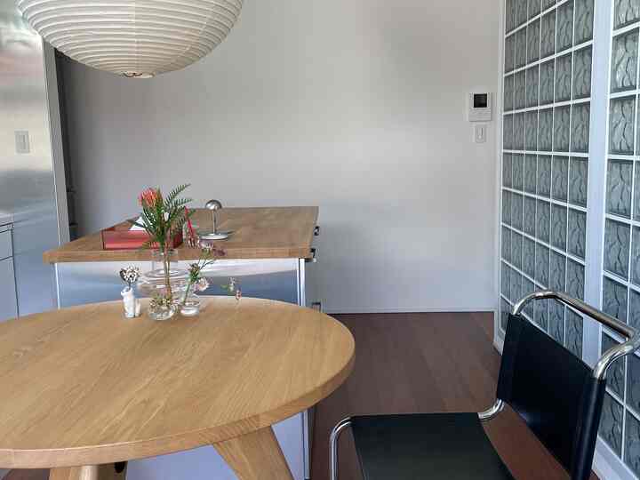 ナチュラルな木目調と白を基調としたモダンなダイニング、丸いダイニングテーブルと黒い椅子が配置されたすっきりとした空間