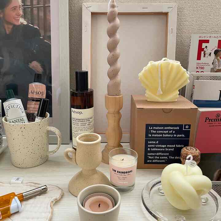 アイボリーとナチュラルカラーのキャンドルとセラミックキャンドルホルダーが配置されたシンプルなテーブル上の装飾品