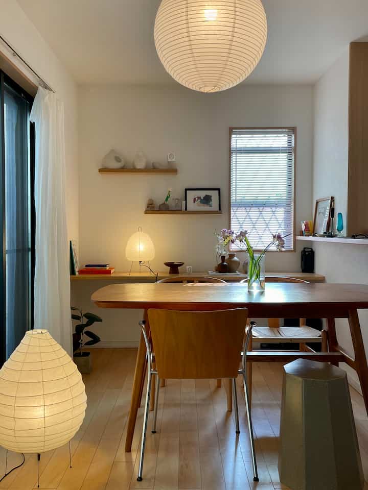 Natural dining room with white walls and wood tone table, warm paper lamps creating cozy atmosphere.