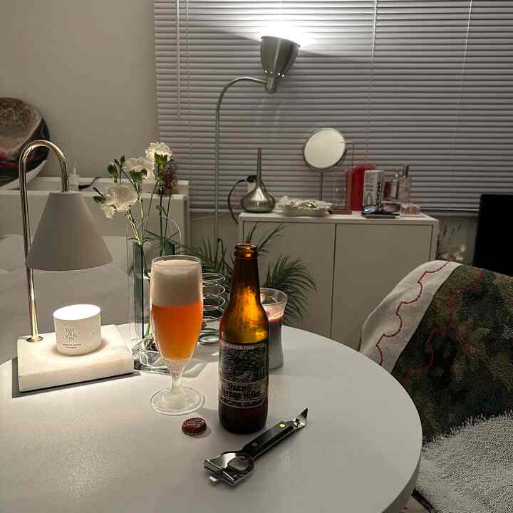 White and silver toned living room featuring table and floor lamps, beer and flowers on a simple cozy table