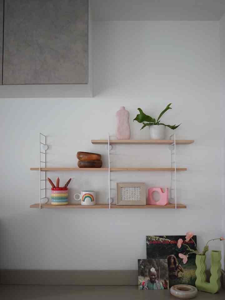 ナチュラルな木目調と白い壁のキッチン棚が配され、ミニマルな装飾品で整えられた清潔感のあるインテリア