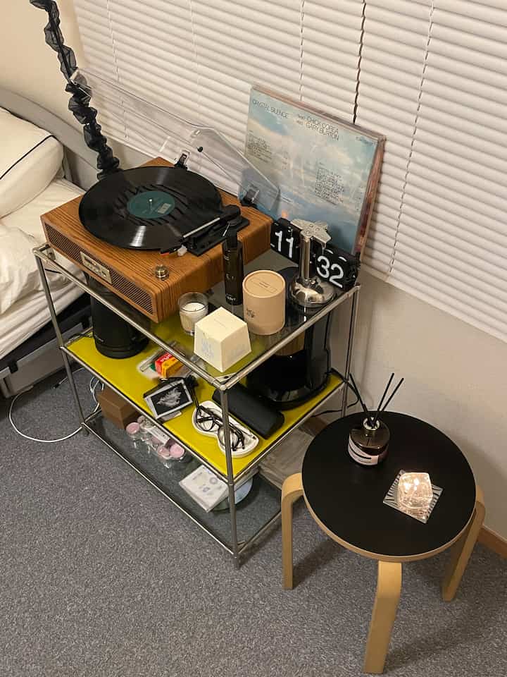 ナチュラルカラーと黒のラックにレコードプレーヤーとキャンドルが配置されたリビングスペース