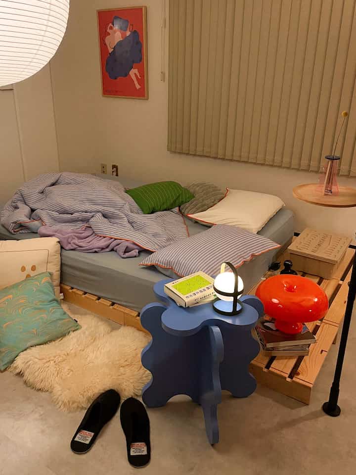 Natural-toned bedroom featuring a blue bed and uniquely shaped side table creating a cozy atmosphere