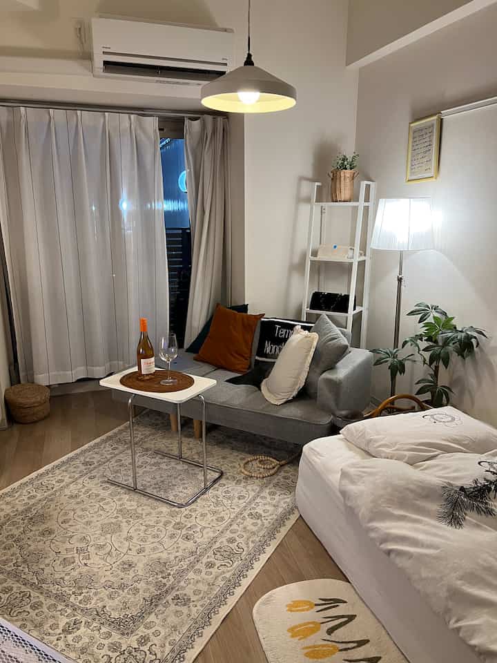 白とグレーの色調のリビング、ソファとサイドテーブル、ラグが配置されたシンプルで落ち着いた雰囲気のインテリア