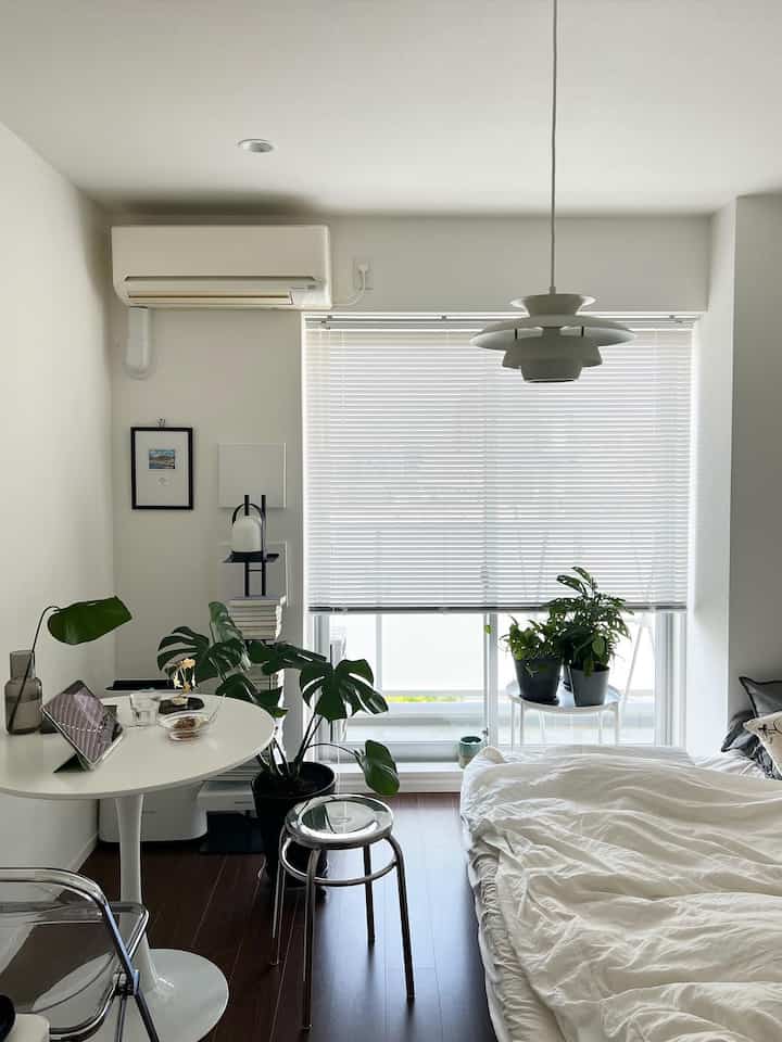 White and dark brown toned studio bedroom featuring nightstand, plants, and simple natural decor