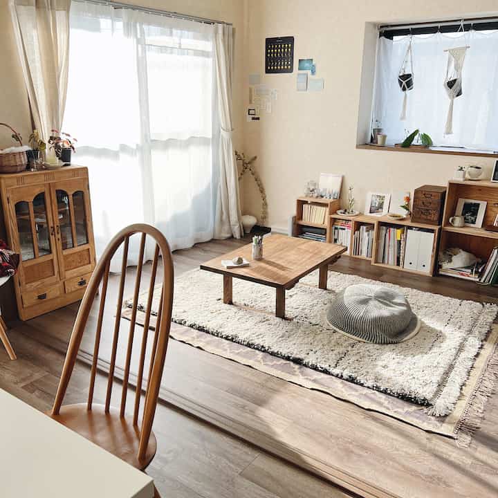 ブラウンの木製家具と白いカーテン、ラグが調和したナチュラルな印象のリビングスペース