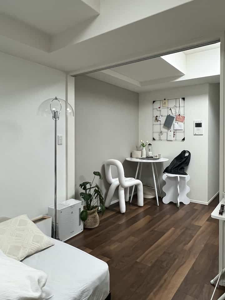 ホワイトと木目調のモノトーンの小さなリビング、モダンな家具と植物が配置された雰囲気のある空間