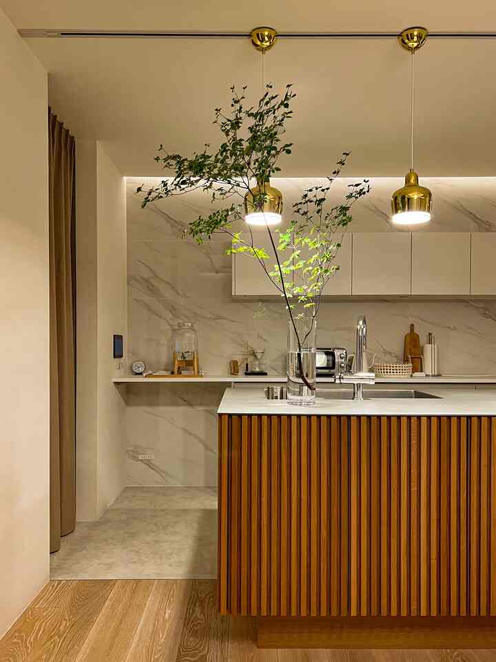 木目調と大理石模様が調和したキッチン、ゴールドのペンダントライトとシンクが配置された温かみのあるモダンな空間