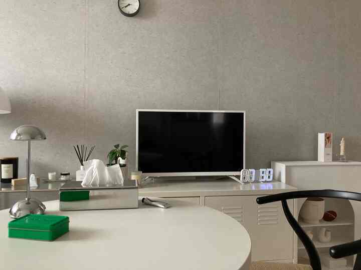 Modern living room with silver and white tones featuring a central TV, table lamp, and clean minimalist decor