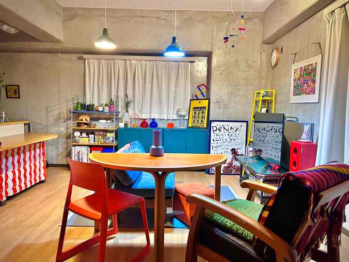 ブルーとレッドのトーンが特徴的なワンルームのリビング、木製家具とキャビネットが配置された落ち着いたインダストリアルな雰囲気のインテリア