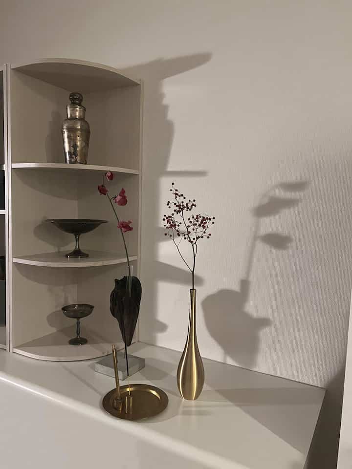 ゴールドとシルバーのオブジェが配置されたナチュラルトーンのリビングの棚の装飾空間