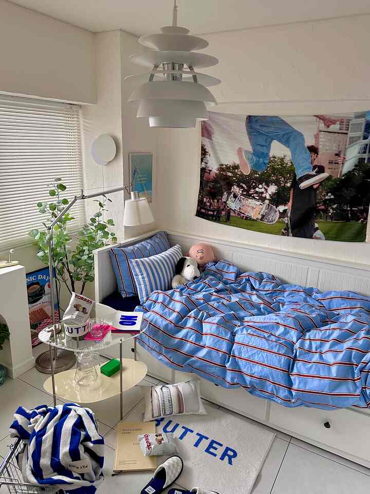 ブルーとホワイトの色調の寝室、ストライプの寝具と収納付きベッドが配置された居心地の良いインテリア