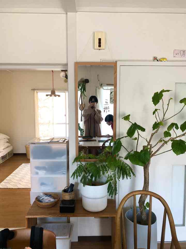 A white and wood tone living room featuring a wooden framed mirror and plants creating a natural atmosphere