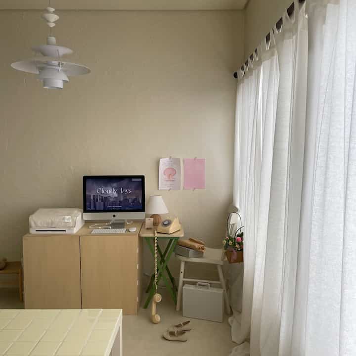 Natural beige and white toned compact home office featuring desk, chair, and curtains in a clean setting