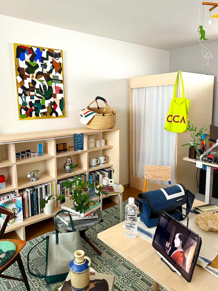 白い壁と木目調家具が配置された一人暮らしの1LDK空間、書棚やデスクがあるナチュラルな雰囲気の部屋