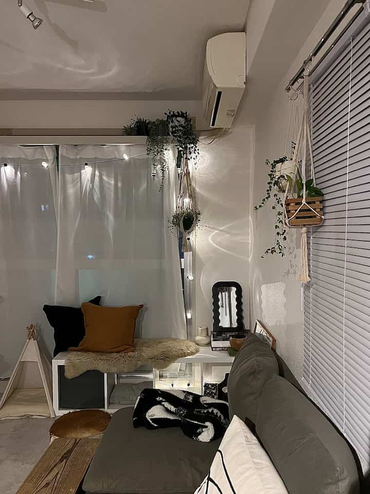 温かみのあるベージュと緑の植物が調和した居心地の良いリビング、自然な雰囲気のソファとクッションが配置された空間