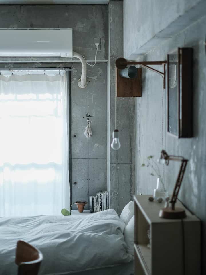 Minimal bedroom featuring white and natural color tones, clean layout with a comfortable bed and simple furnishings